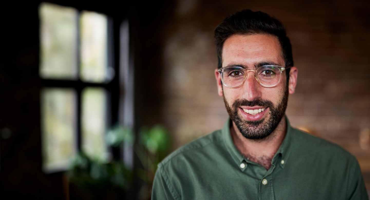 An Adult male with eye glasses, has a full beard, smilling with his teeth